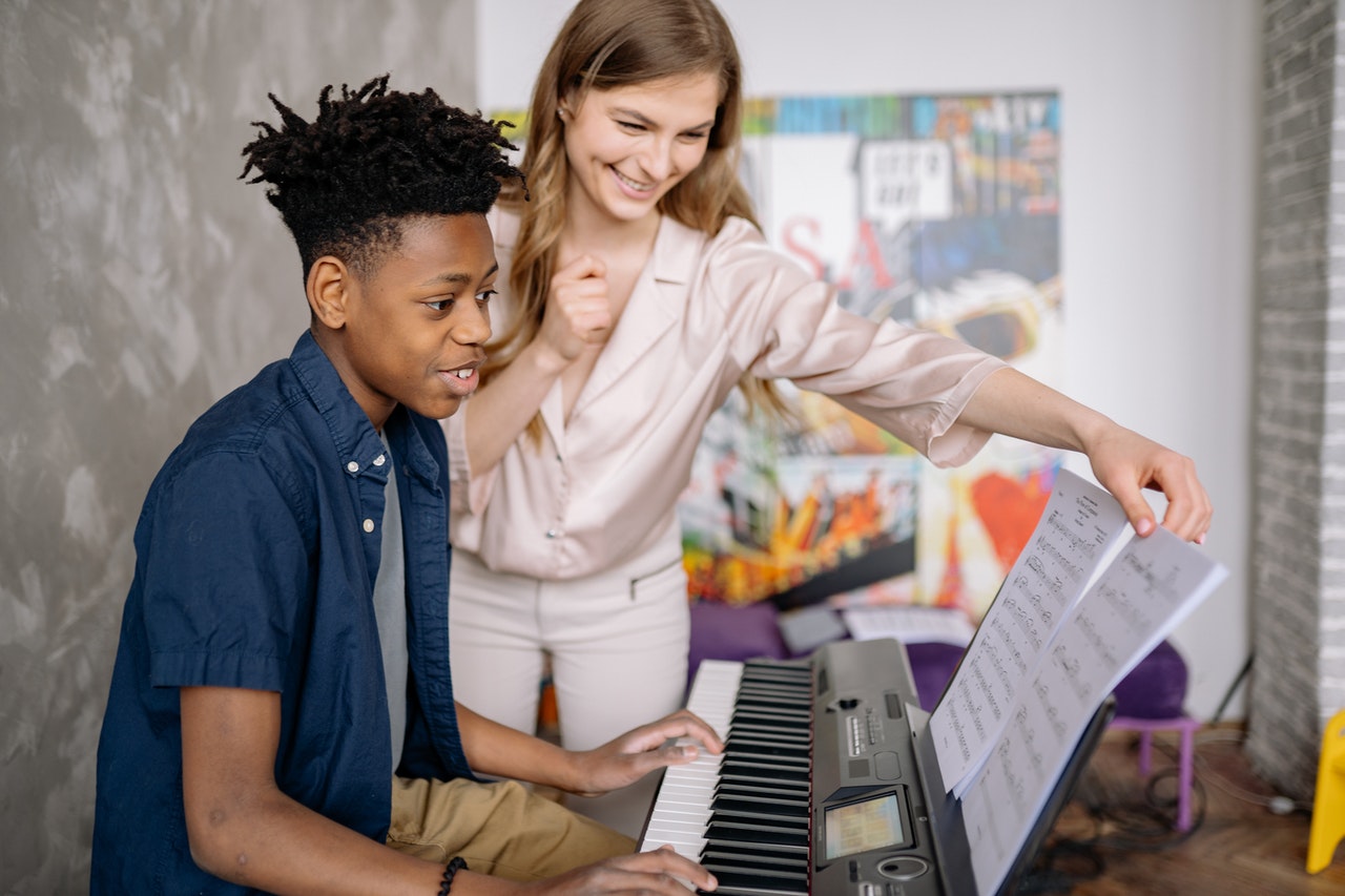 Young musician learning piano in music school - music teacher explains notes privately