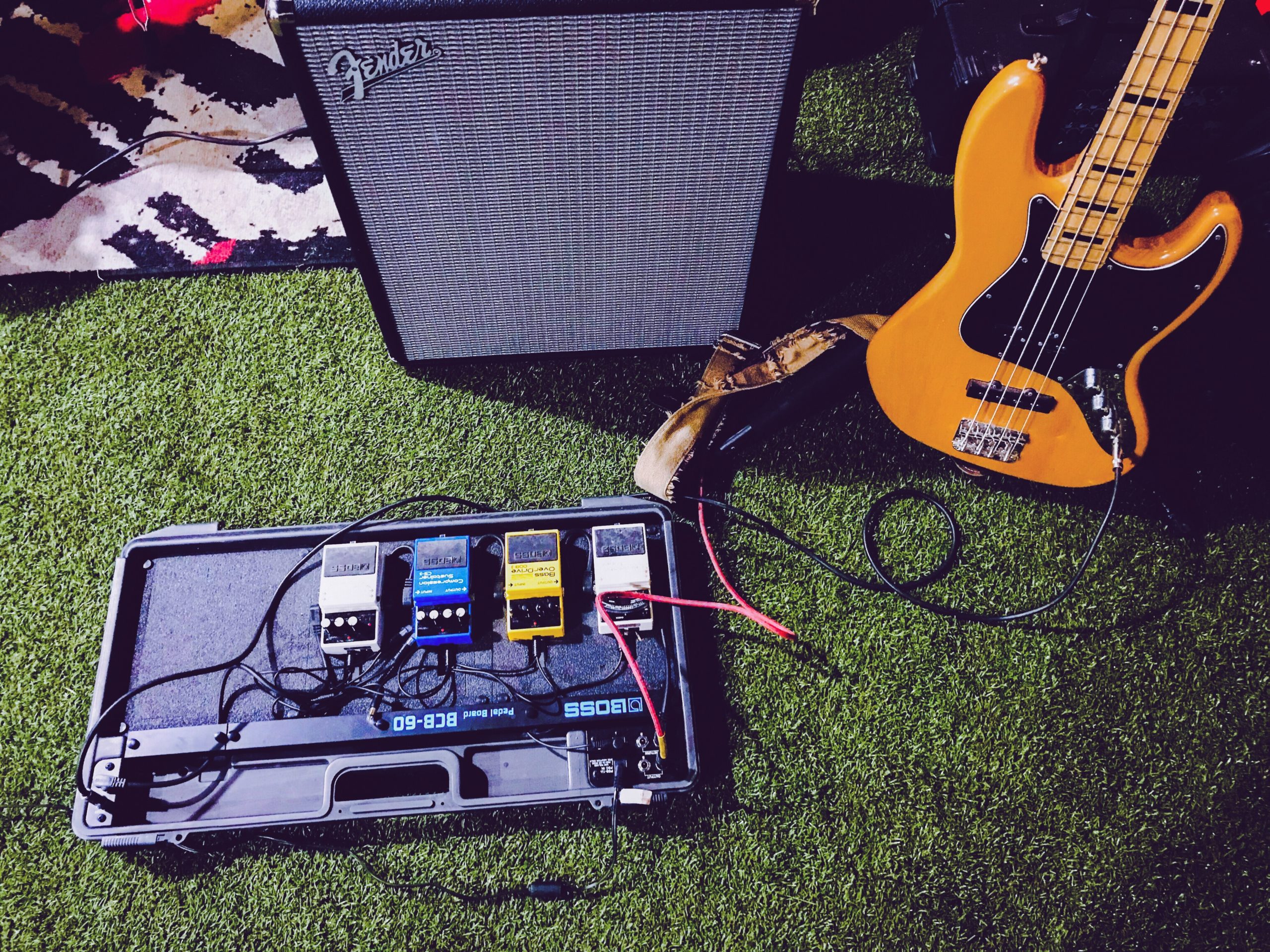Yellow electric bass guitar next to black Fender guitar amp
